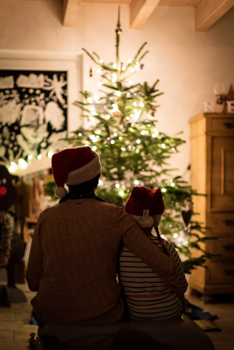 father and son sitting in front of christmas tree
